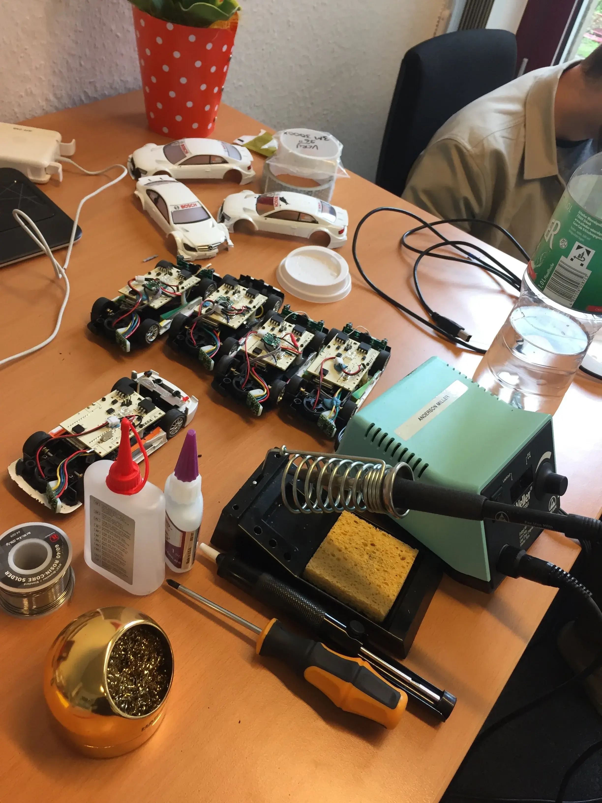 Workbench with RC car chassis, soldering station, and components mid-assembly