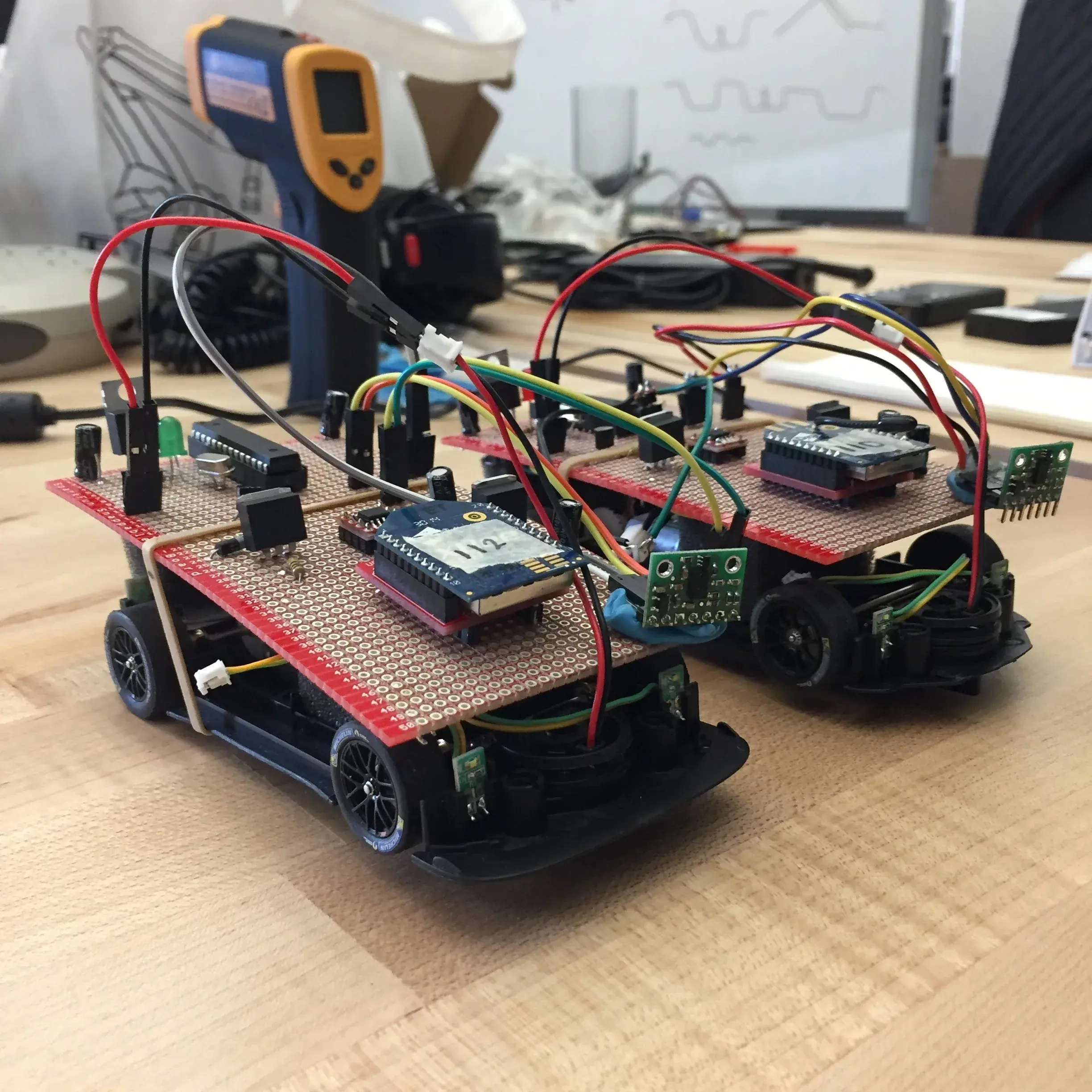 Close-up of a single vehicle with custom wiring, sensor board, and perfboard mounted to the chassis