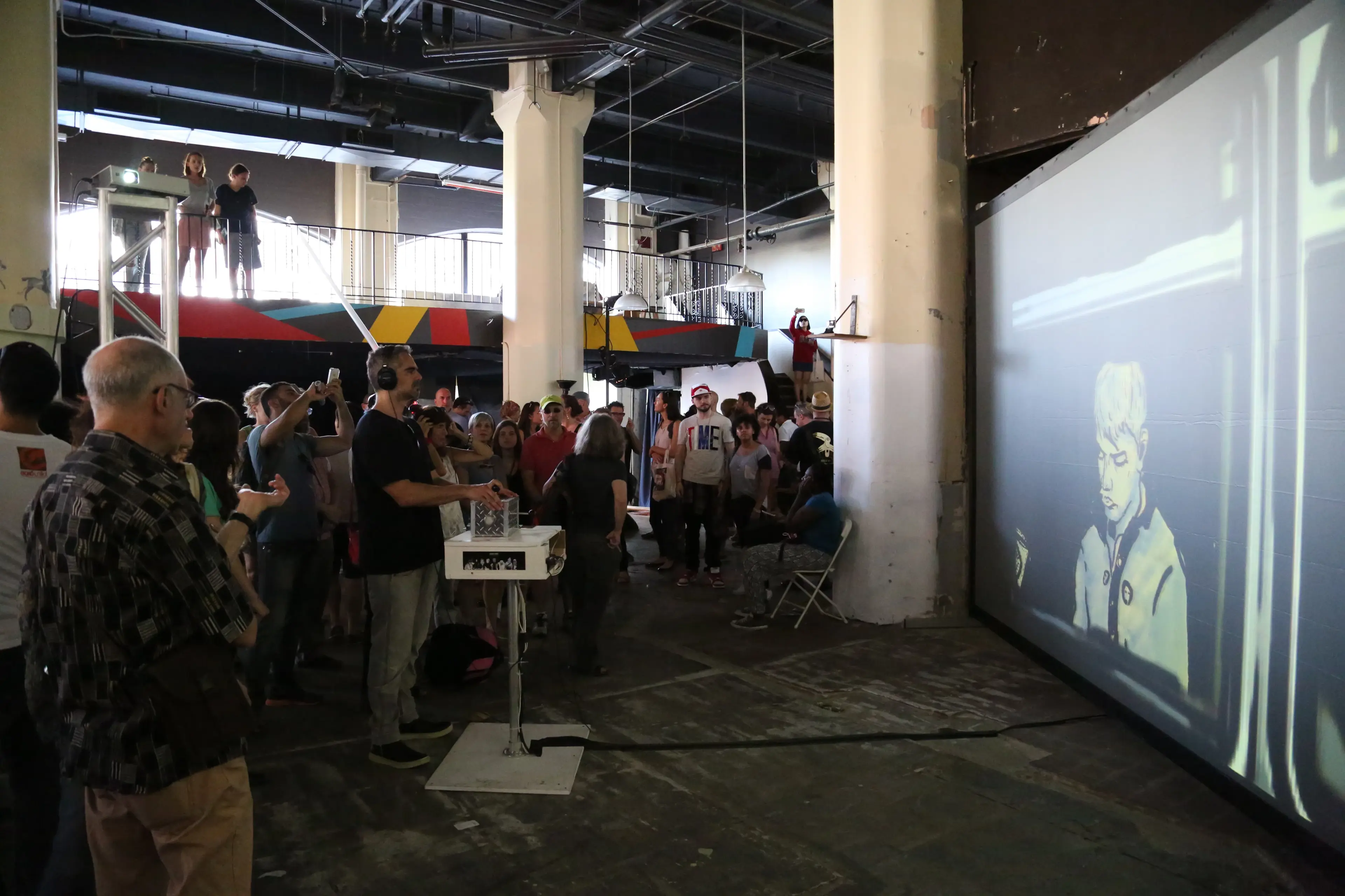 Large crowd watching Subway Stories projected onto a warehouse wall at the DUMBO Arts Festival in Brooklyn